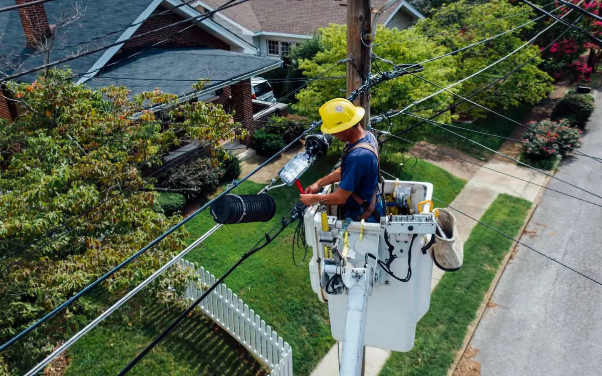 Lineman in a bucket working on lines above a residential street
