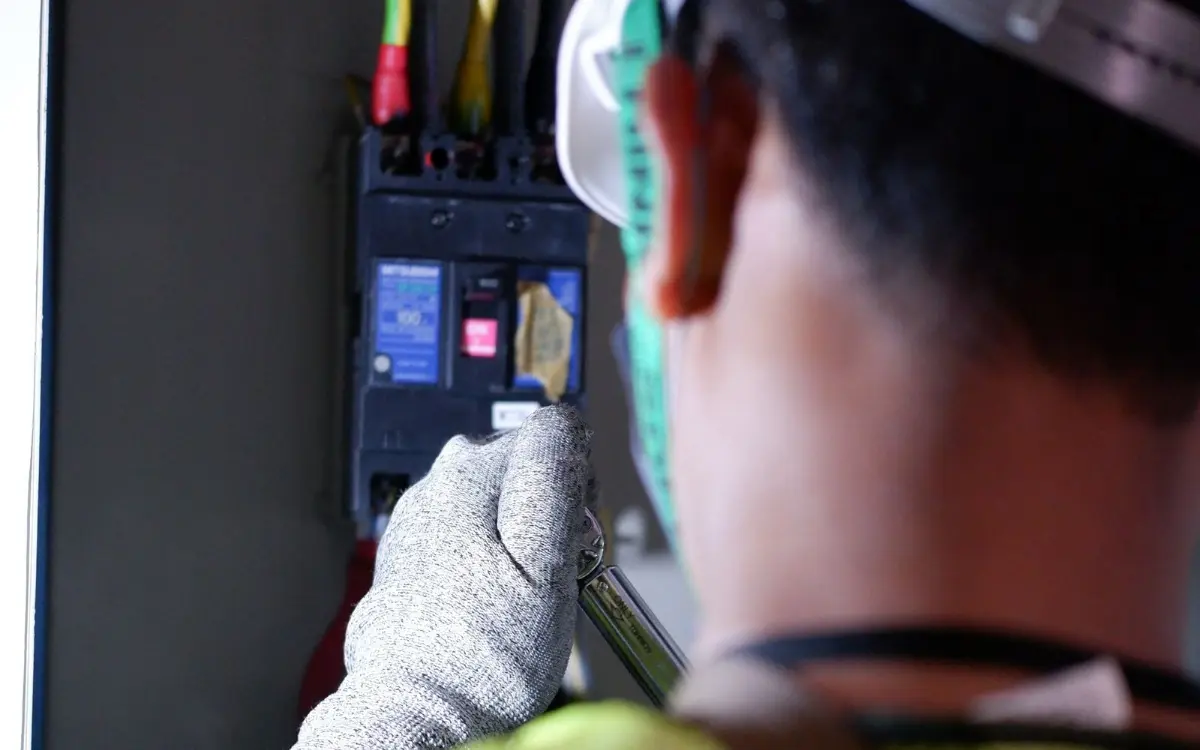Electrician in a hi-vis vest working on breakers