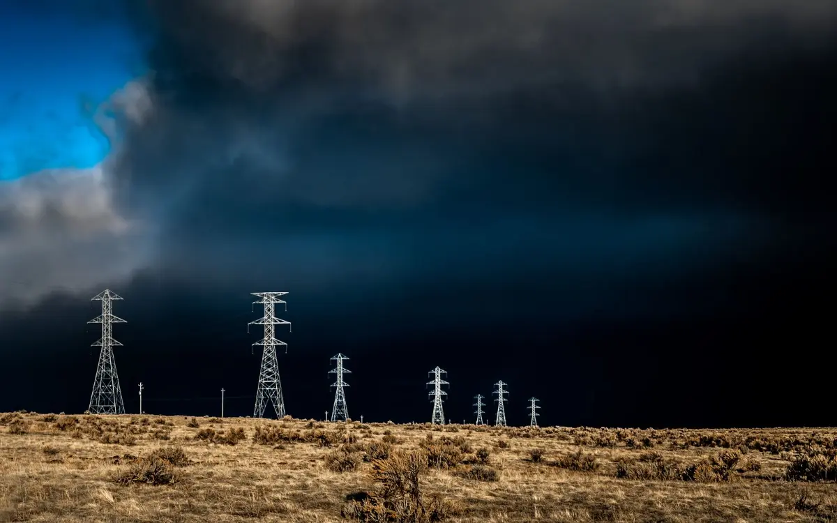 Transmission towers under a dark storm sky