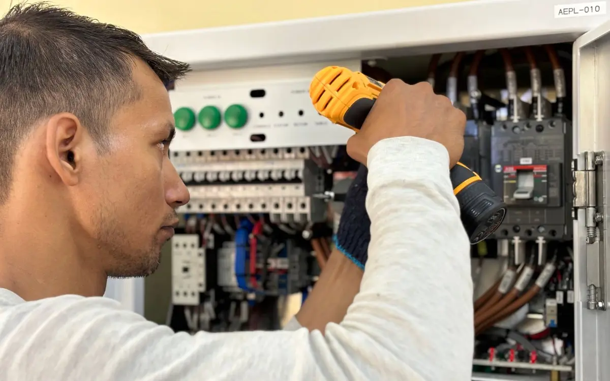 Technician tightening terminals in a generator control panel