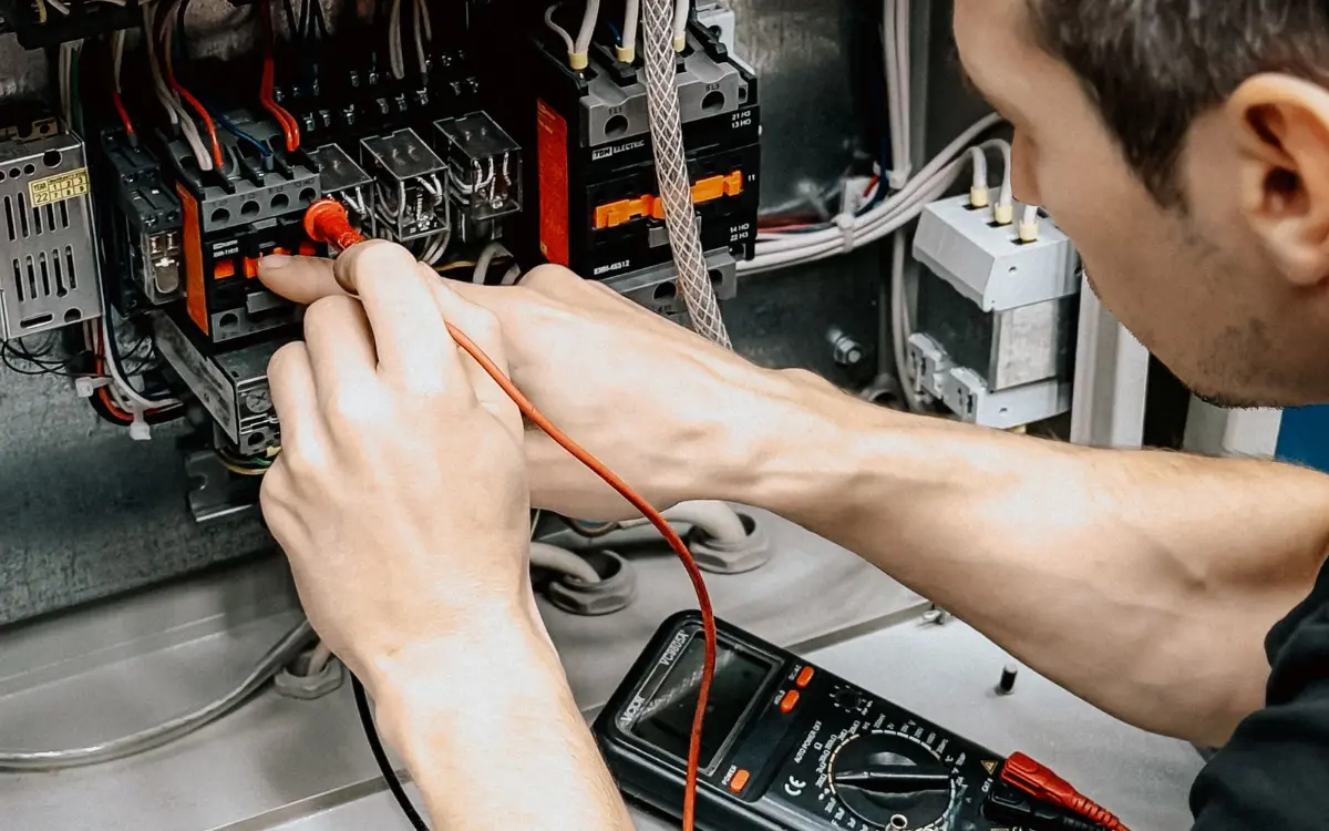 Electrician measuring a control panel with a multimeter